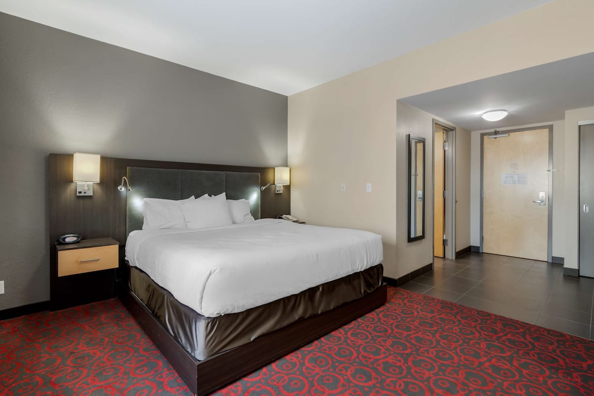 Ein Hotelzimmer mit einem großen Bett, Nachttischen und einem roten Teppich mit Muster.