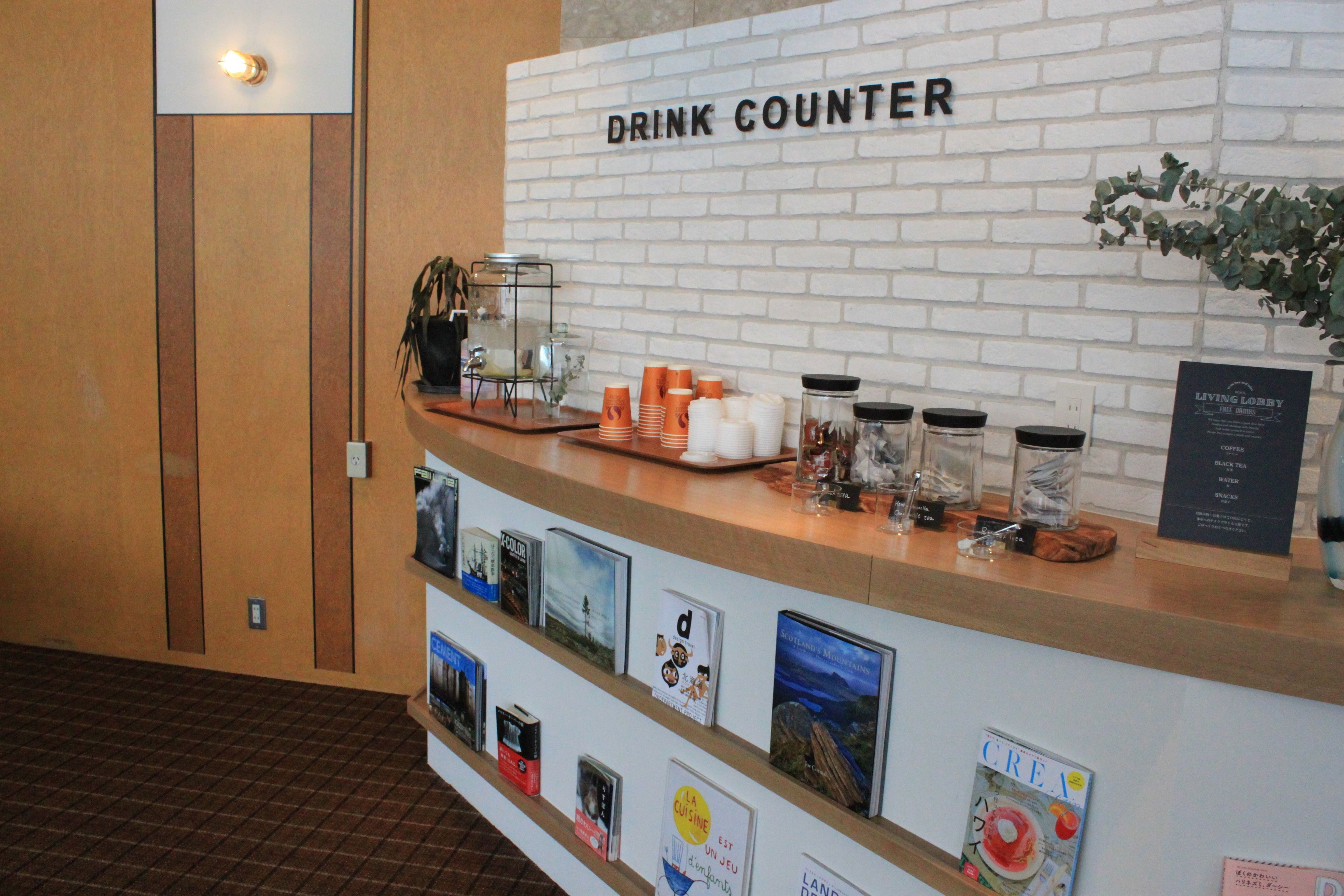 A drink counter with a white brick wall, a sign reading "DRINK COUNTER," and various items like cups, jars, and a menu board.