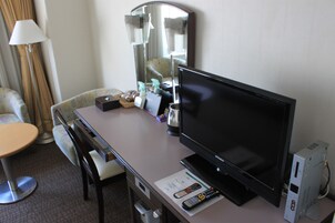Habitación de hotel con escritorio, televisión, computadora y una silla.