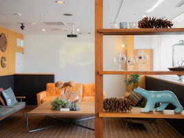 Un interior moderno con un estante de madera que muestra objetos decorativos, un sofá con cojines y una mesa de centro.