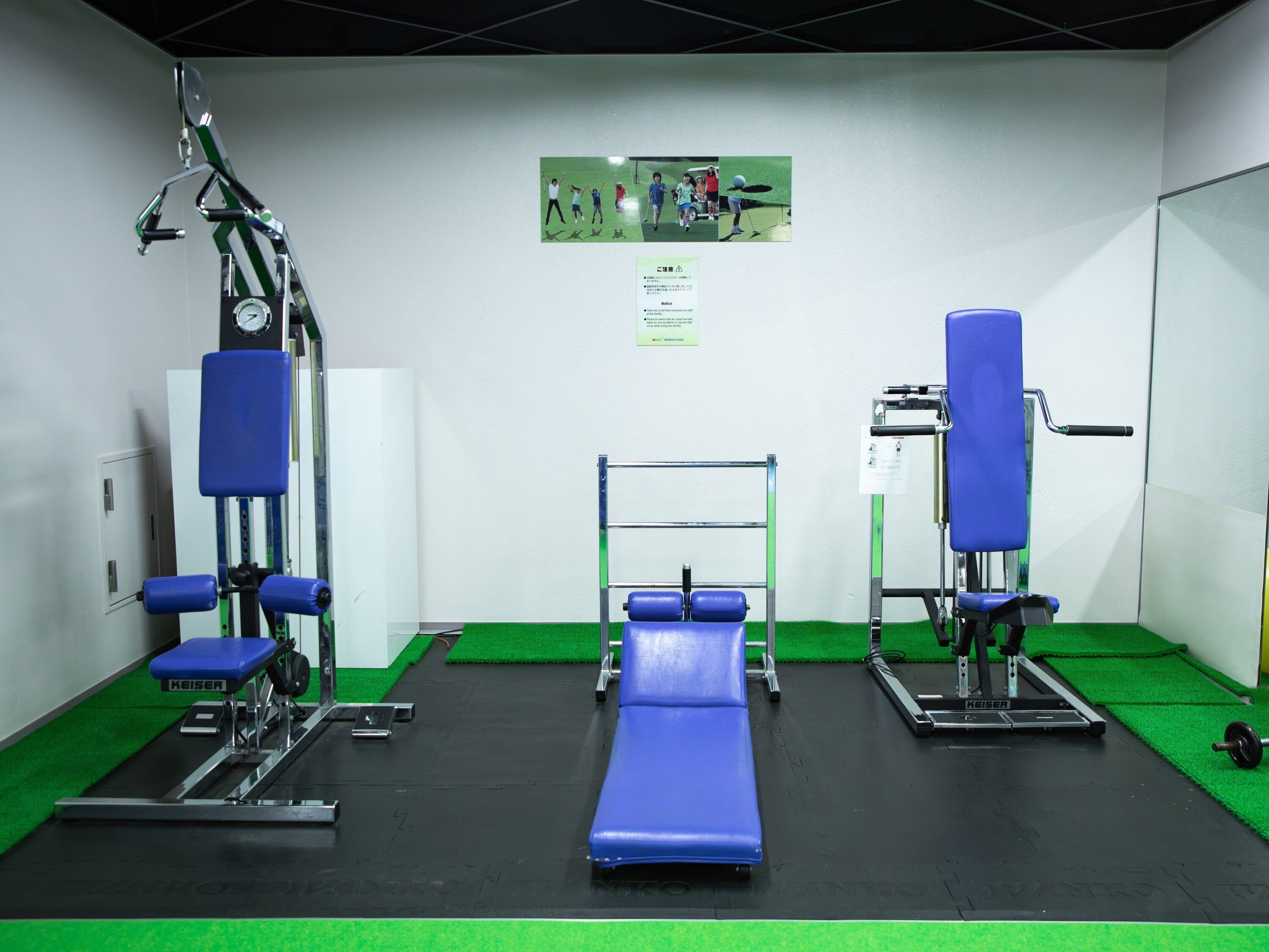 A gym with exercise equipment, a blue bench, and a green floor.
