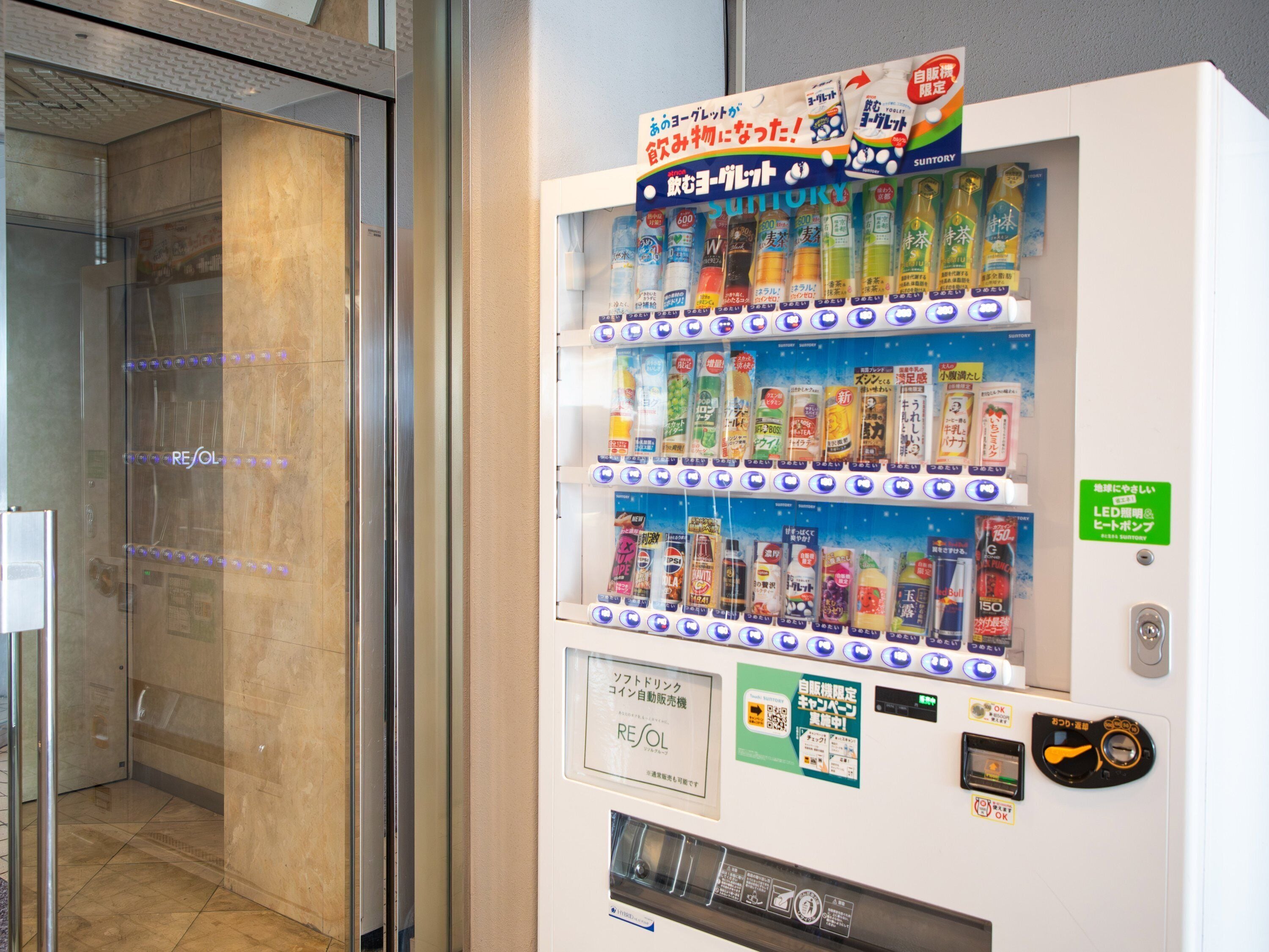 Ein Getränkeautomat mit verschiedenen Getränken und einem Schild, das eine Selbstbedienungszone kennzeichnet.