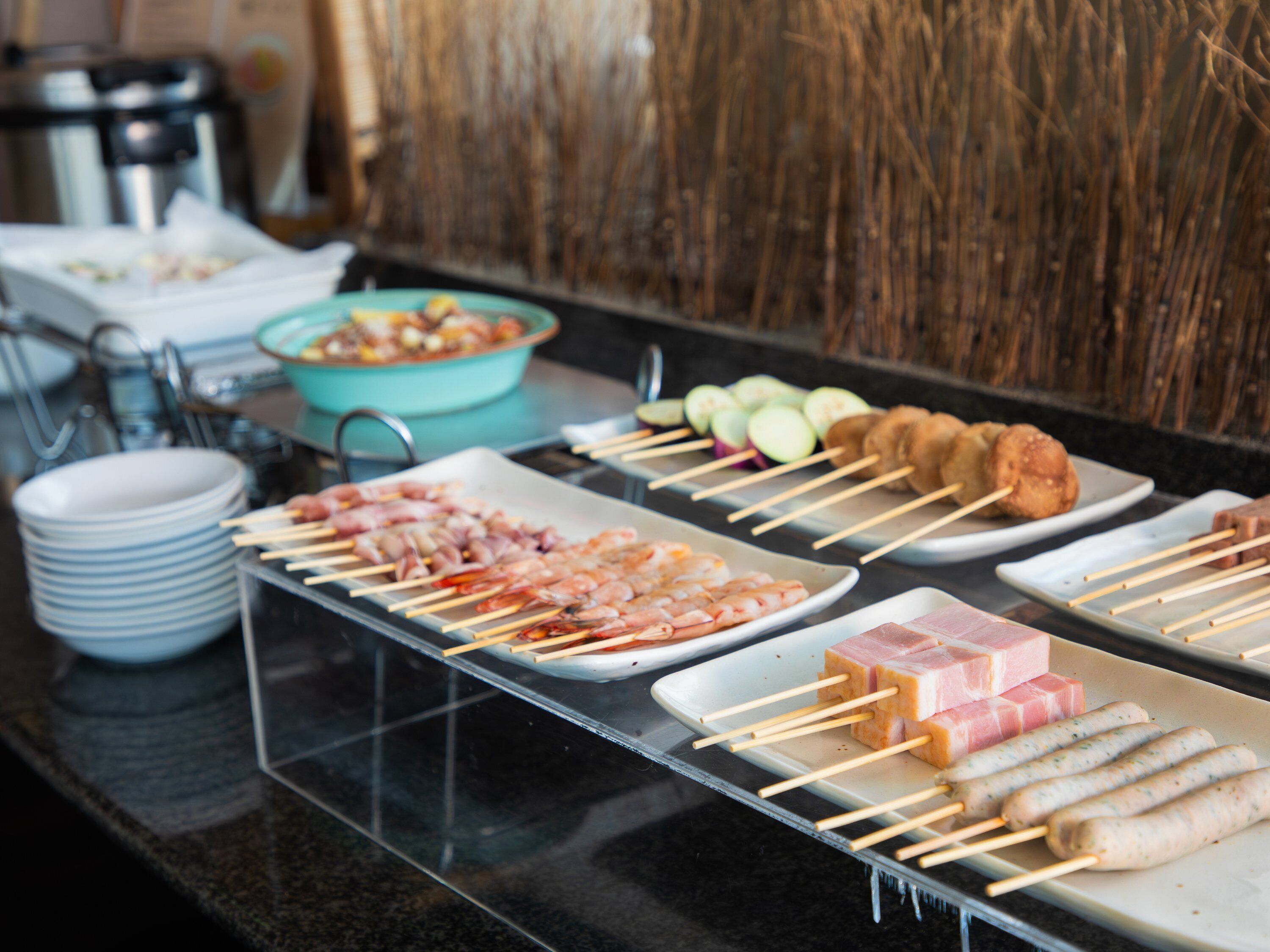 A buffet with various food options including skewered meats and vegetables.