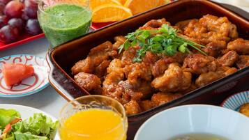 Variedad de platillos, entre ellos un pastel de carne, frutas frescas y un vaso de jugo.
