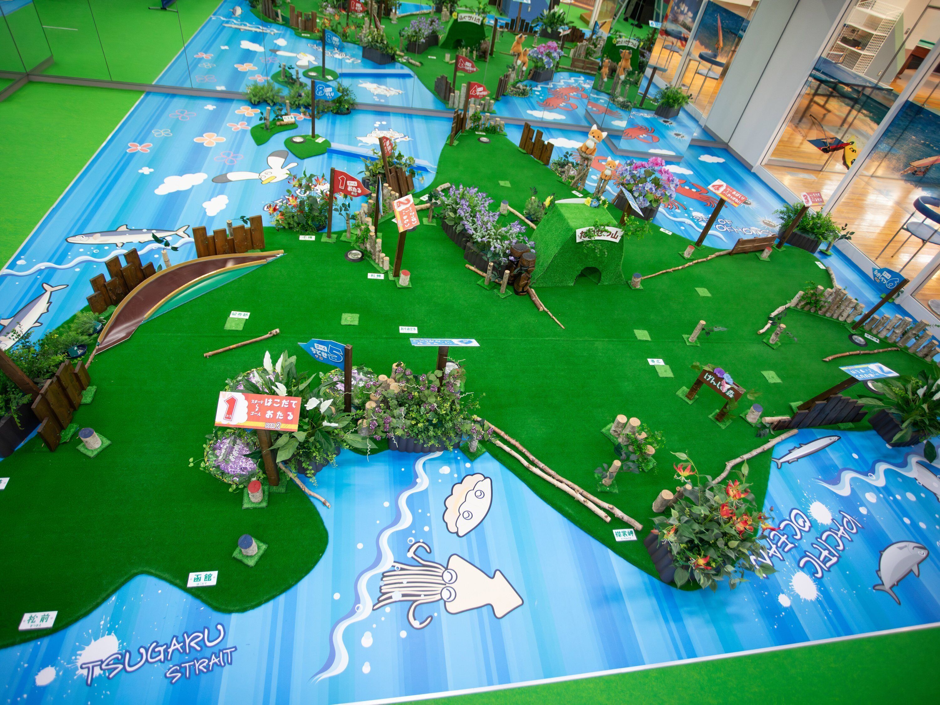 A model of a coastal landscape with artificial grass, plants, and various marine life illustrations.