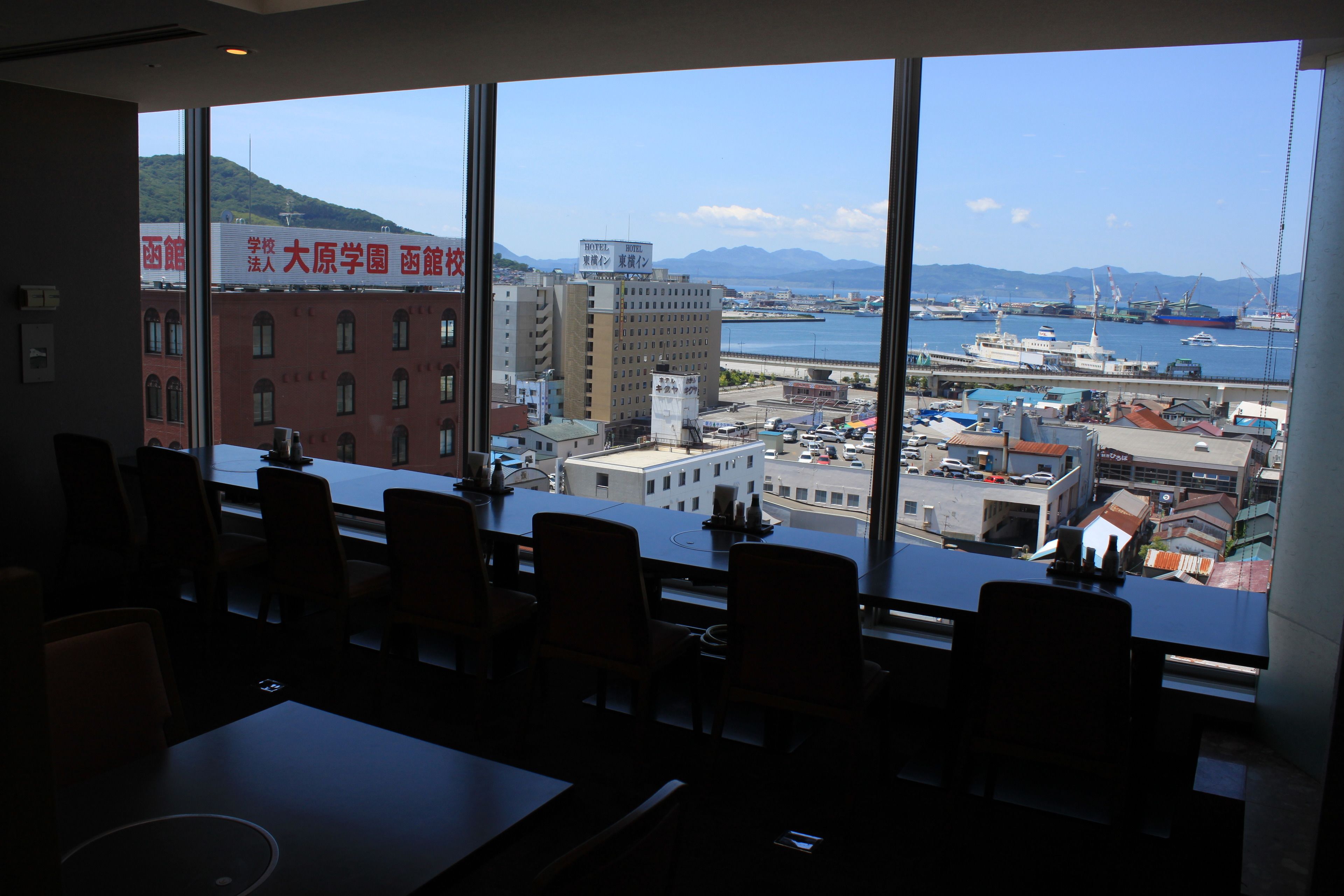 A conference room with a large window overlooking a harbor with boats and buildings.
