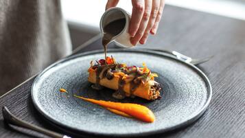 A person pouring sauce onto a dish on a plate.