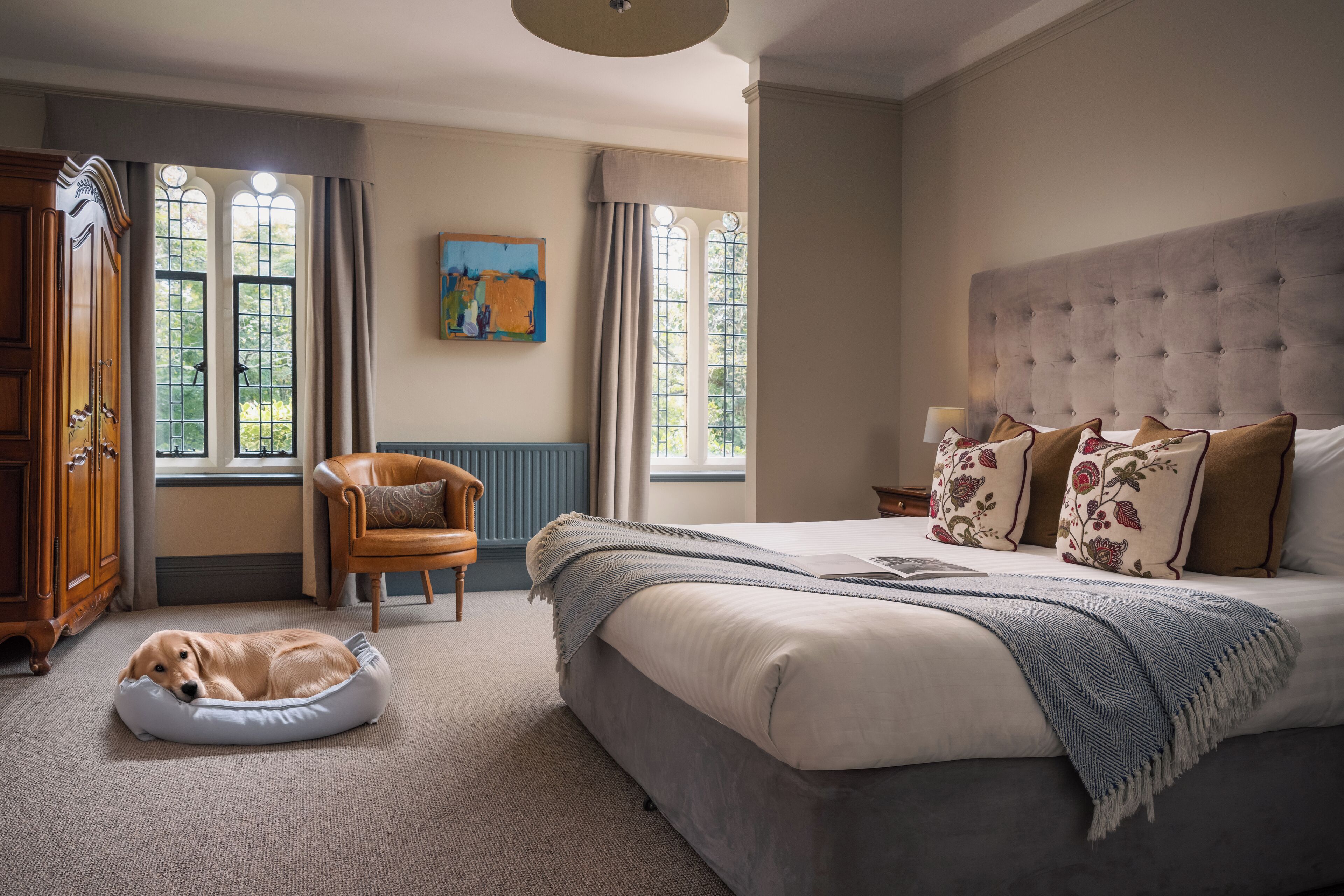 A bedroom with a bed, a dog bed, a chair, and a wardrobe.