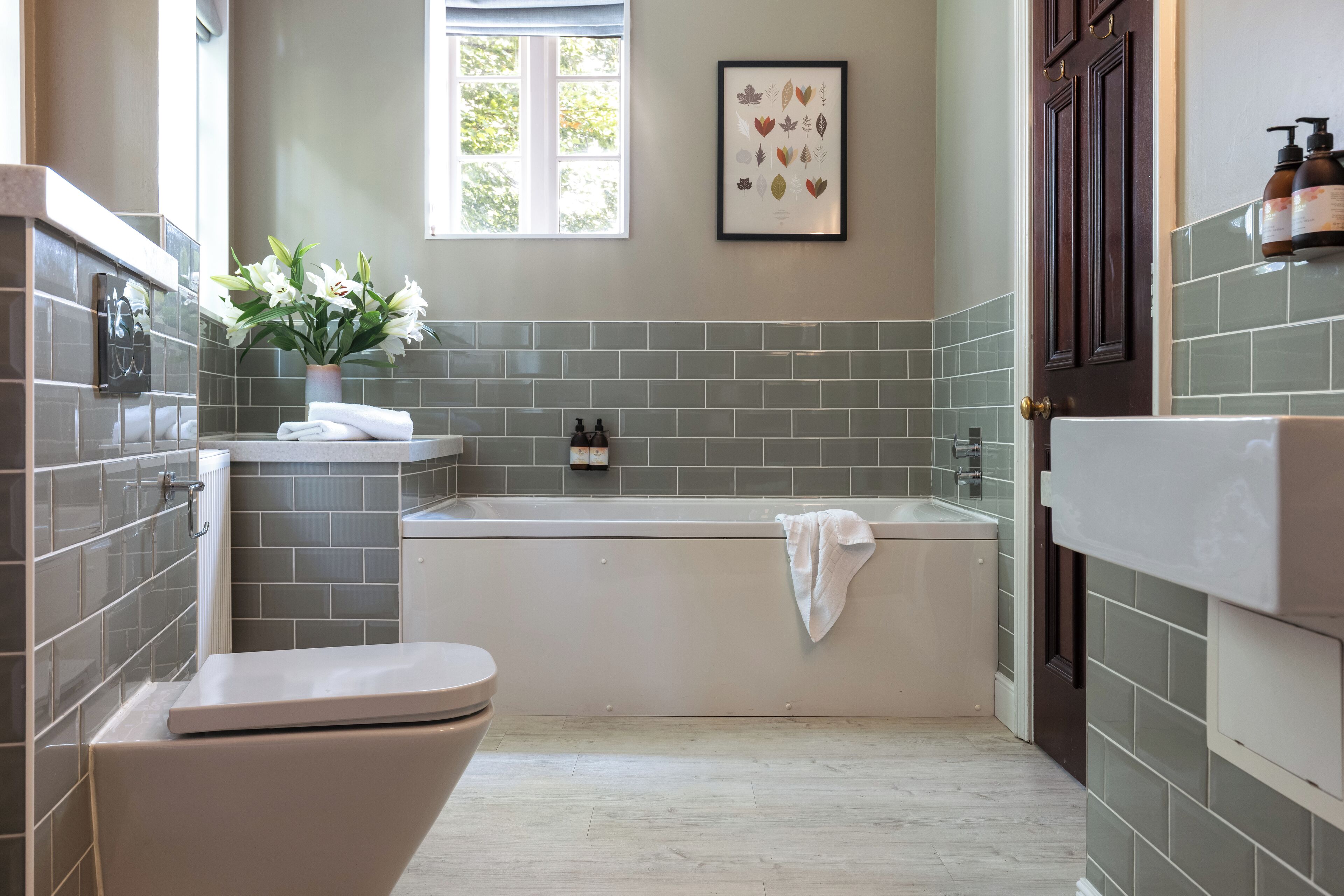 A modern bathroom with a bathtub, toilet, and a window providing natural light.
