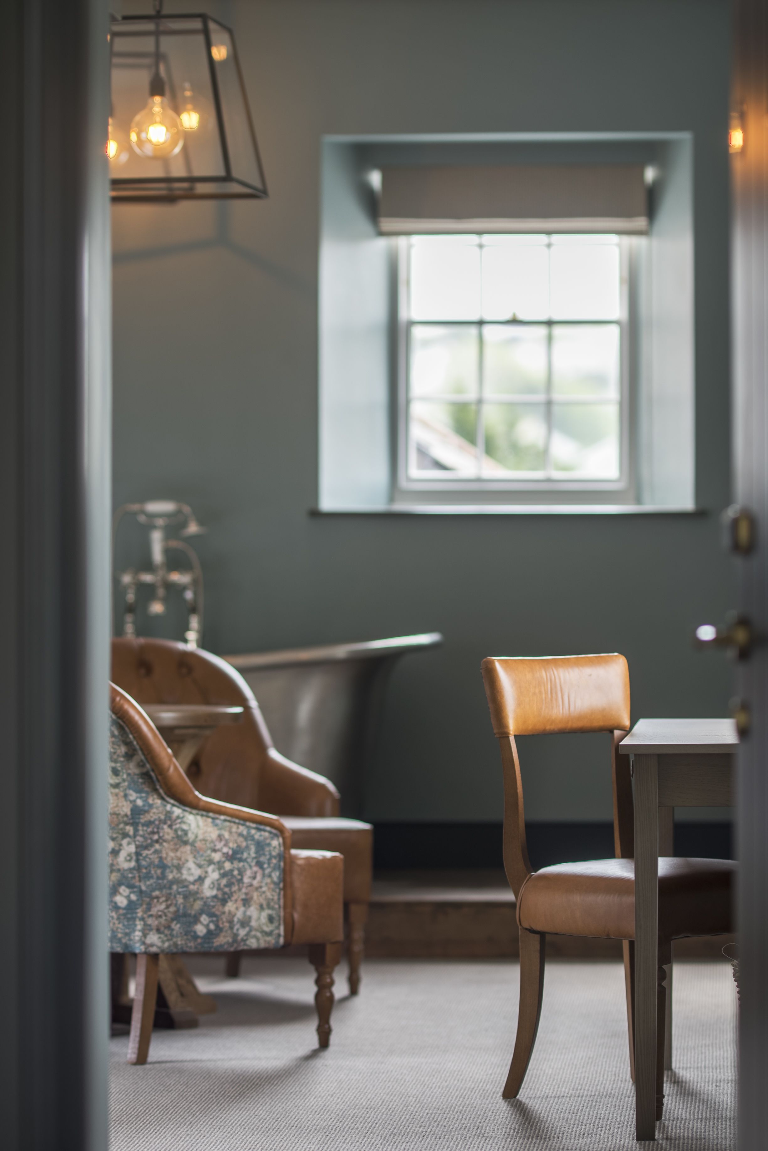 A room with a wooden chair, a small table, and a hanging light fixture.