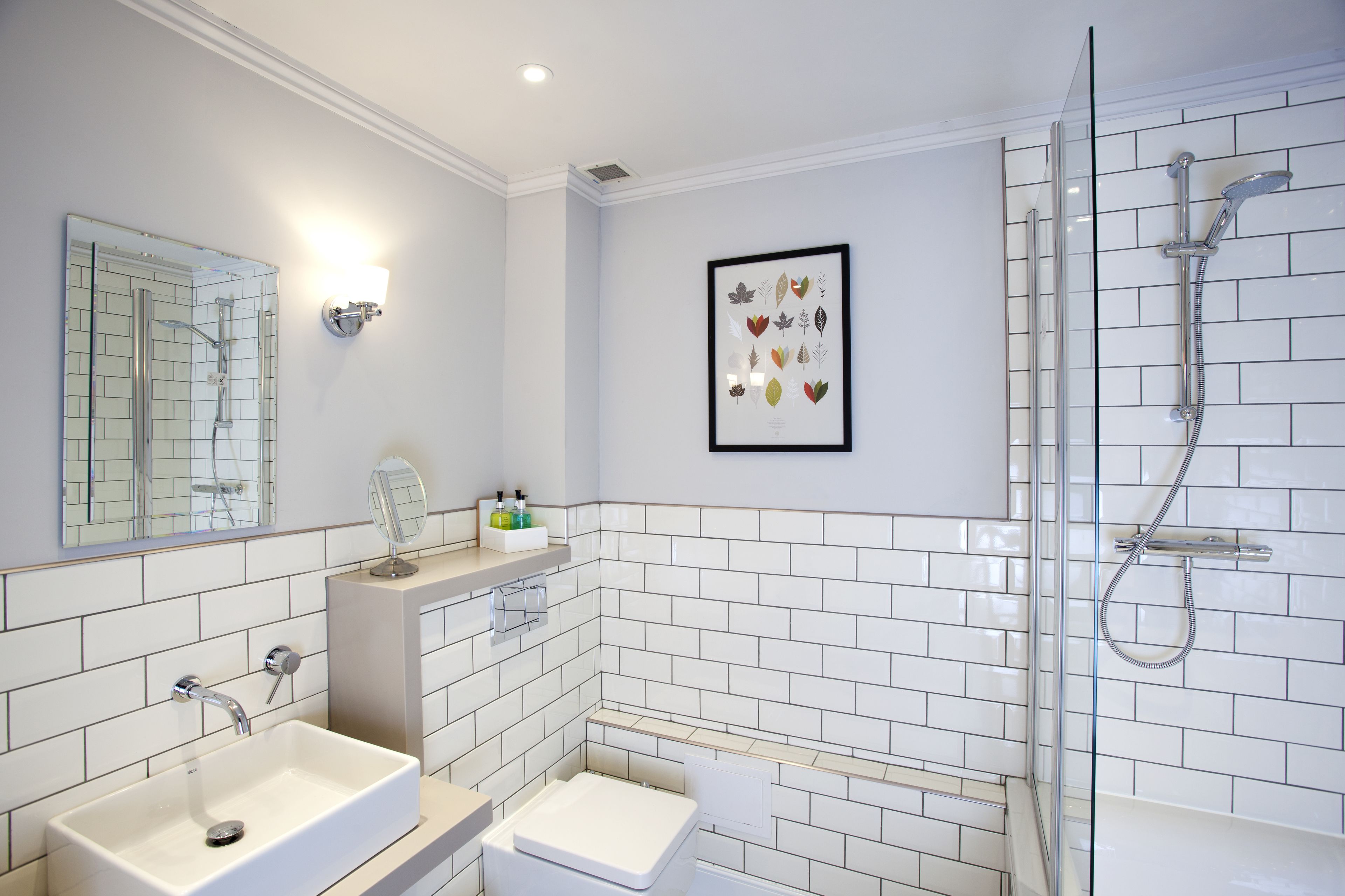 A modern bathroom with a large mirror, a sink, a toilet, and a shower.