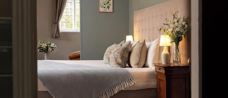 A bedroom with a bed, bedside table, lamp, and a window with curtains.