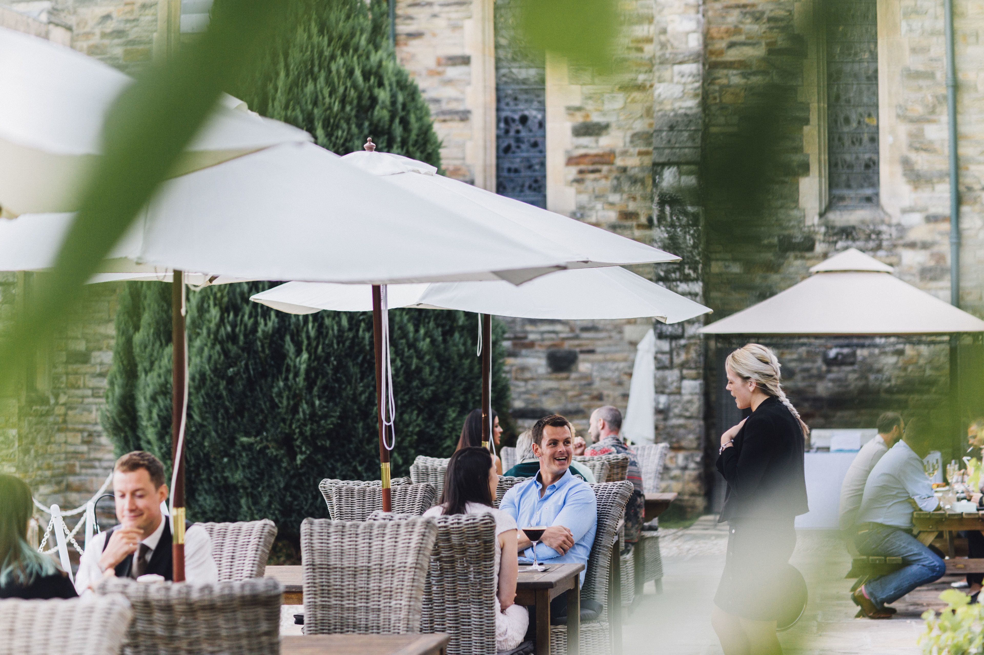 Un área de comedor al aire libre con muebles de mimbre y sombrillas blancas.