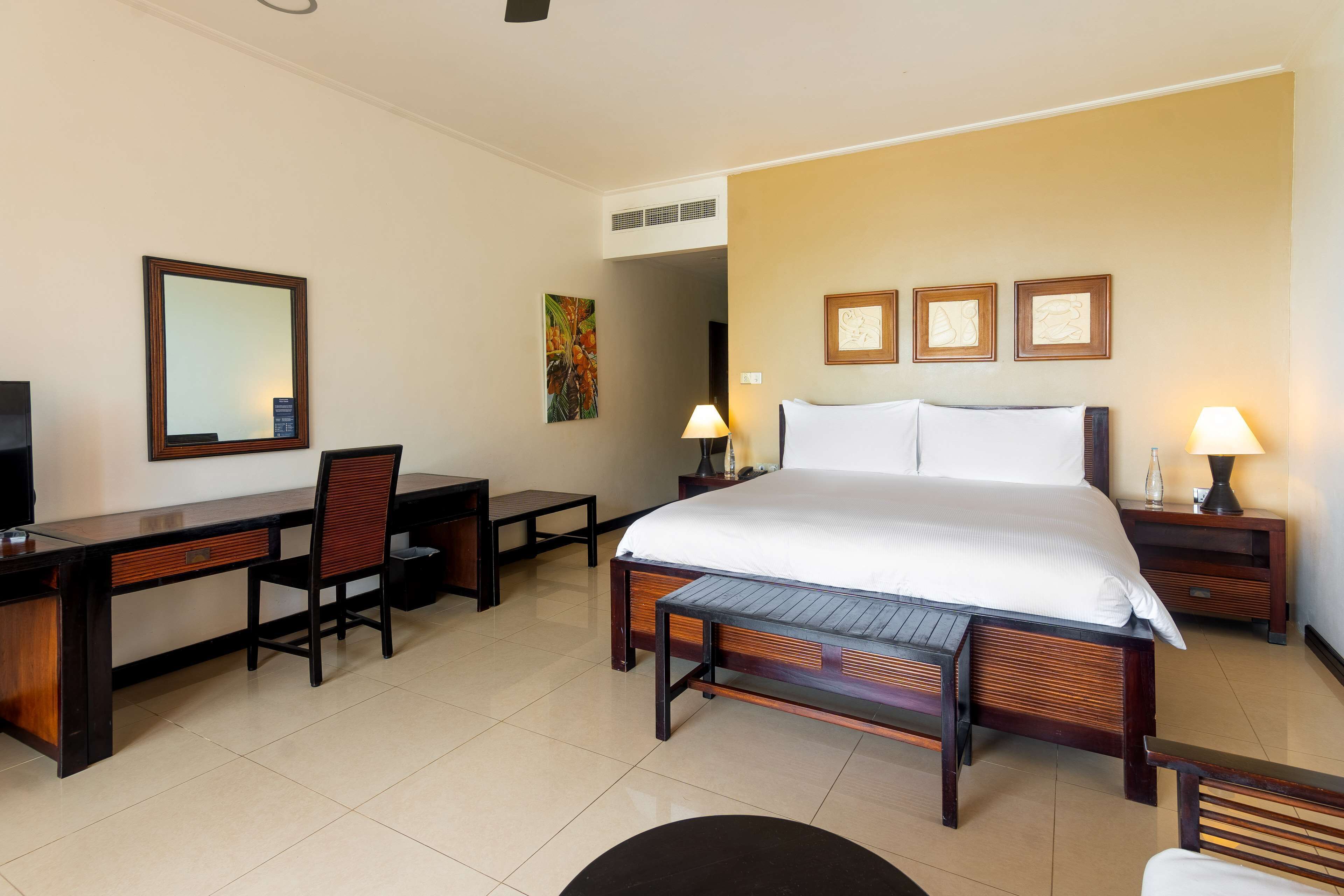 A hotel room with a large bed, a desk with a chair, a TV, and two bedside lamps.