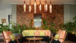 Un área de descanso con una pared de piedra, un letrero que dice "Ocean View Bar" y varias sillas y una mesa.