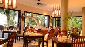 Un restaurante con muebles de madera, ventanas amplias y un tronco de árbol como elemento central.