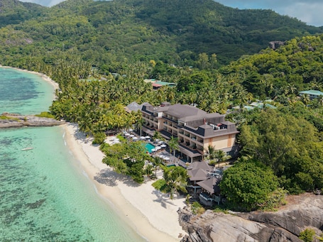A beachfront hotel with multiple buildings, a pool area, and lush greenery.