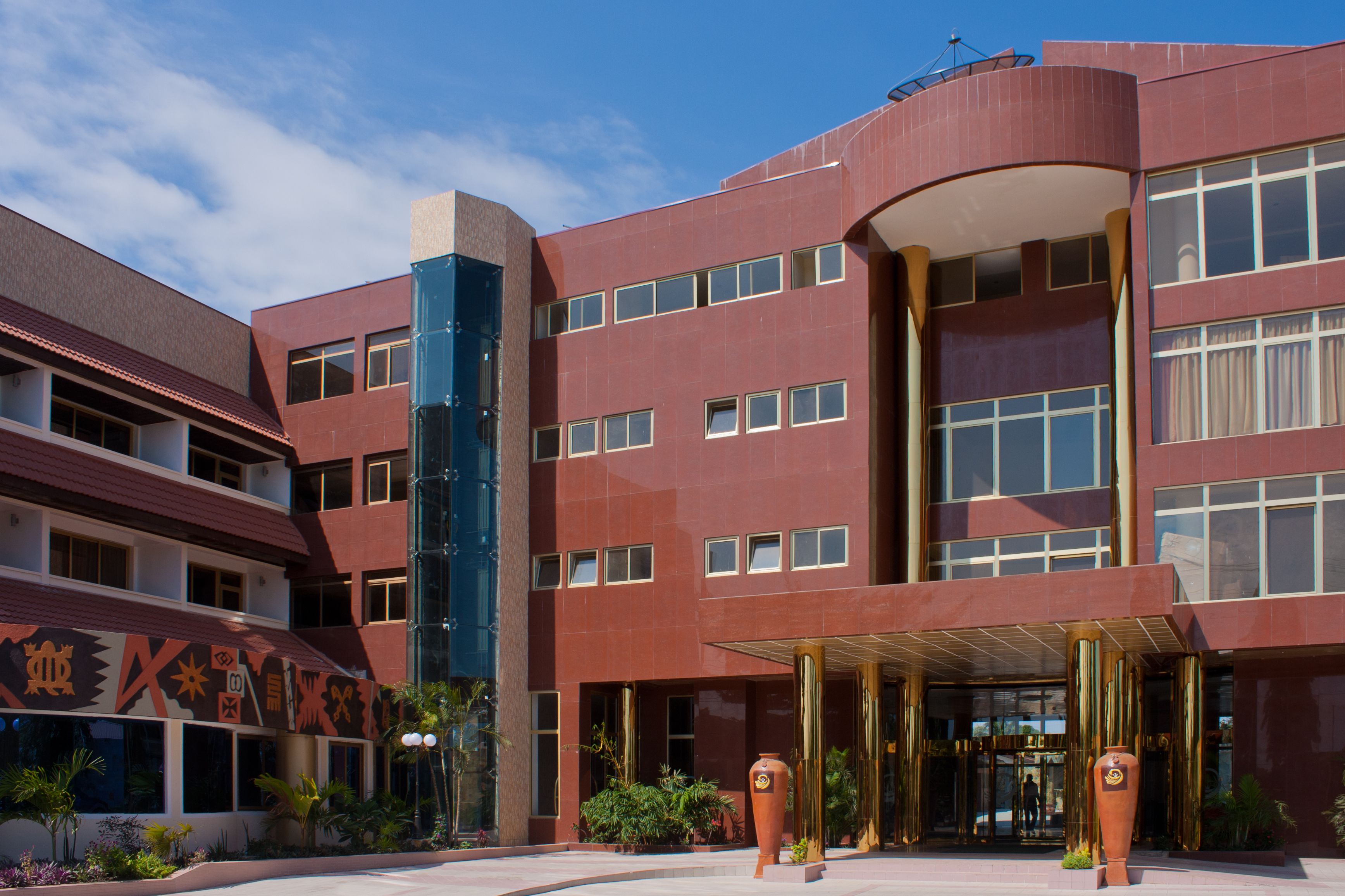 A modern hotel with a curved entrance, multiple floors, and a prominent glass facade.