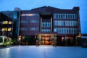 A modern hotel with a prominent entrance, multiple floors, and a well-lit facade.