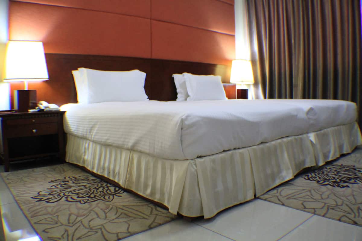 A hotel room with a large bed, two bedside tables with lamps, and a patterned carpet.
