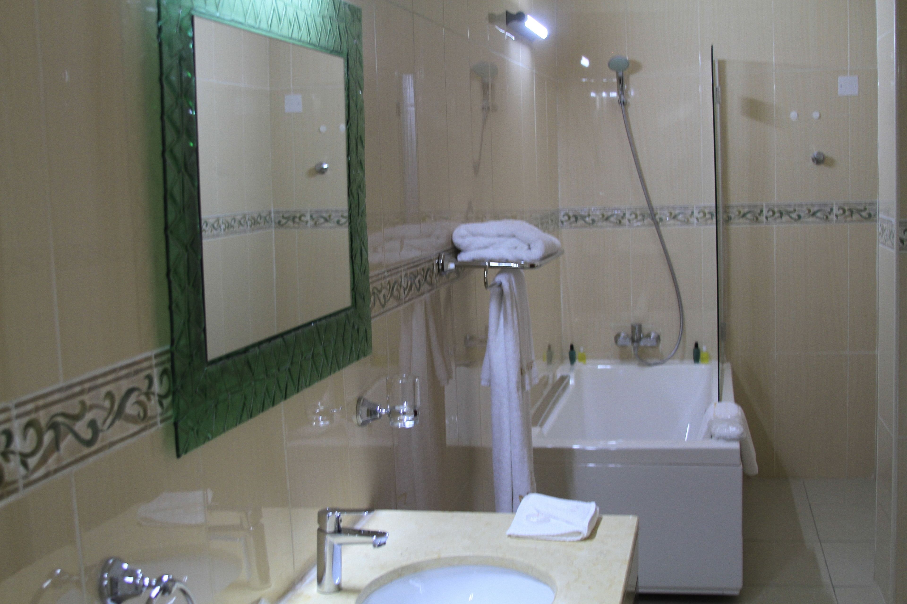 Une salle de bain équipée d’un lavabo, d’un miroir, d’une douche et d’une baignoire.