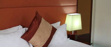 Una cama bien hecha con cabecera marrón y colcha estampada.