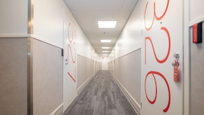 A long, narrow hallway with a grey carpet and white walls. - Omena Hotel Jyväskylä (Jyväskylä)