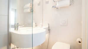 A modern bathroom with a white sink, glass shower enclosure, and a toilet. - Omena Hotel Jyväskylä (Jyväskylä)