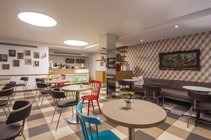 Un comedor moderno con varias mesas y sillas, un sofá y un muro con estampado.