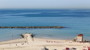 Une plage avec une tour de surveillance pour les sauveteurs, une digue rocheuse et des chaises longues.