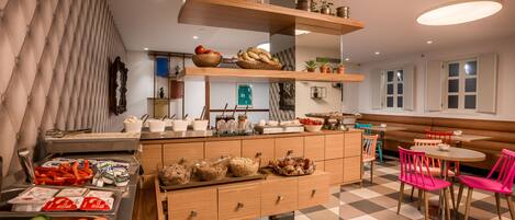 A modern kitchen with wooden cabinets, a central island, and a dining area with pink chairs.