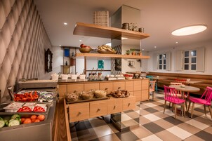Una cocina moderna con armarios de madera, una isla central y un comedor con sillas rosadas.
