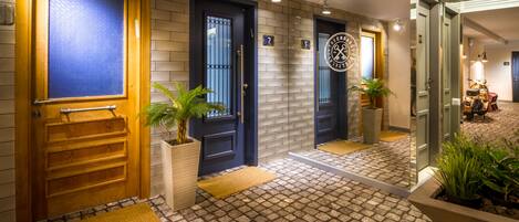 A hotel entrance with three doors, a tiled floor, and potted plants.