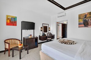 Ein Hotelzimmer mit Bett, Schreibtisch, Stuhl, Fernseher, Spiegel und Bildern an den Wänden.