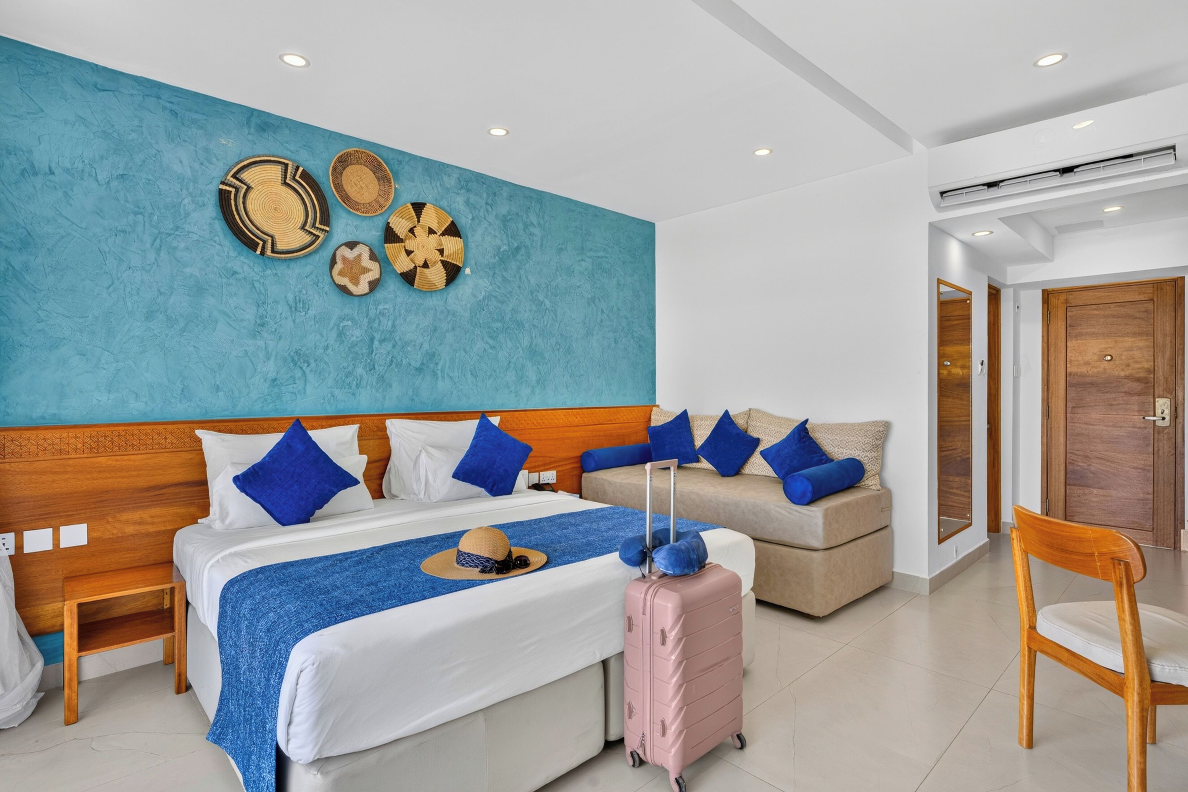 Una habitación de hotel con una cama grande, un sofá, una silla y una pared con adornos.