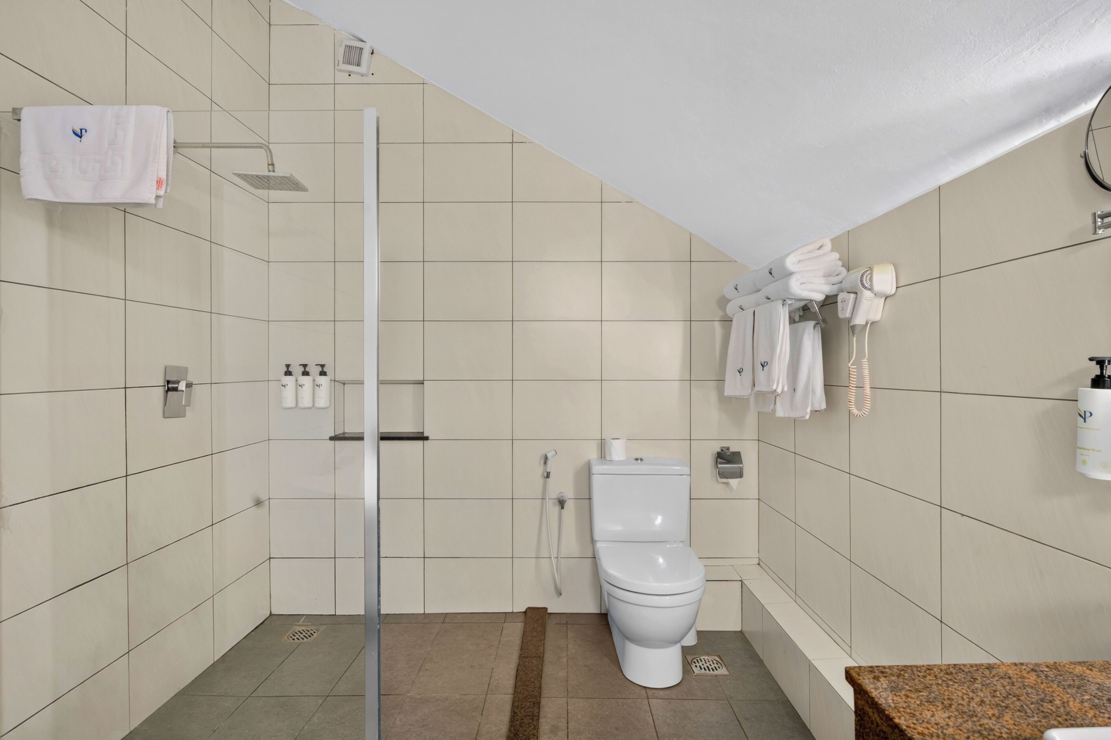 A bathroom with a toilet, a shower, and a sink.