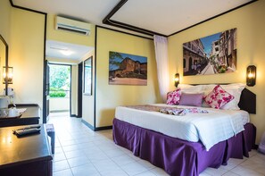 Une chambre d’hôtel avec un lit, un bureau avec un téléphone et un tableau au mur.