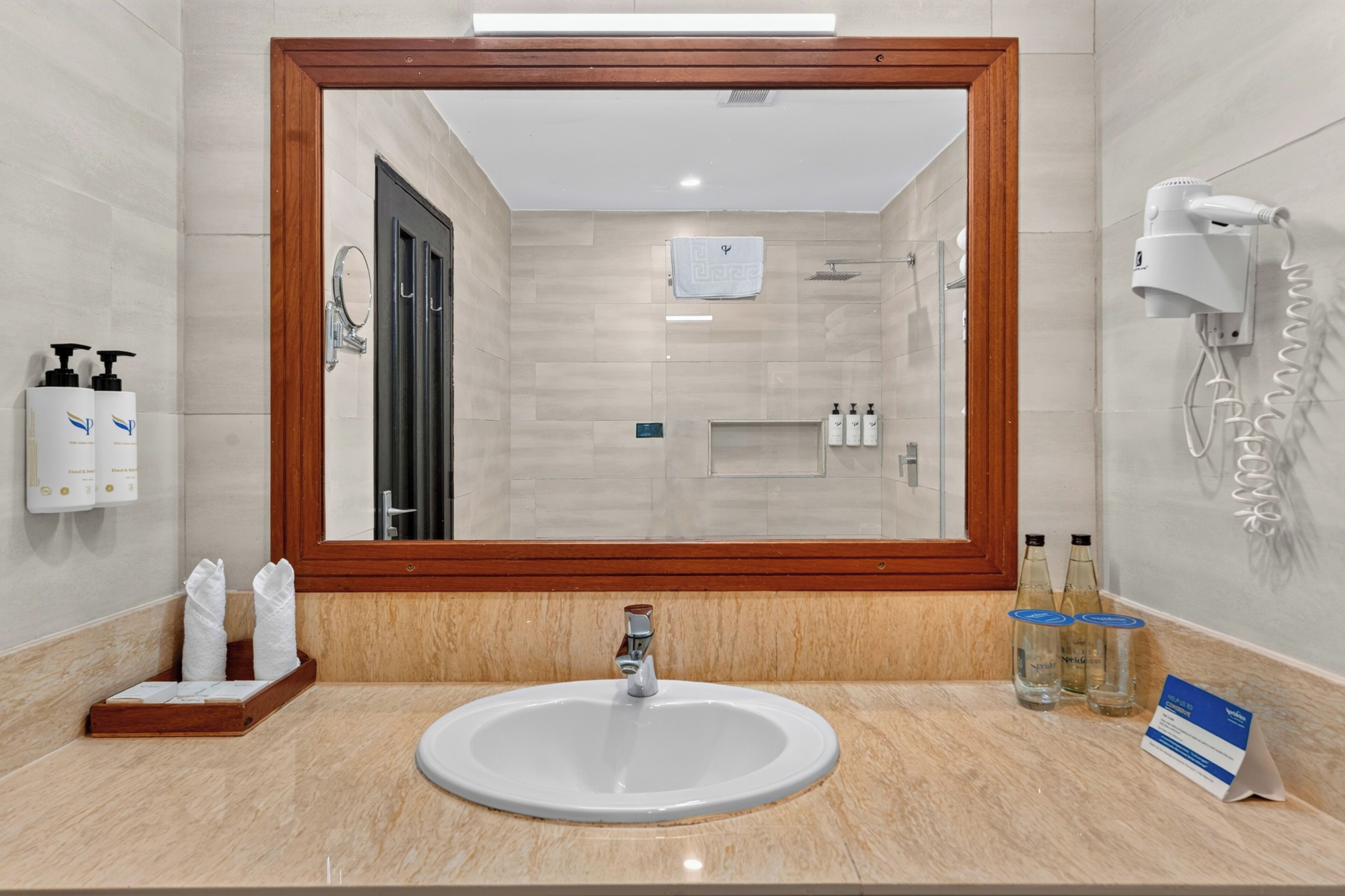 A bathroom with a large mirror, a sink, a towel rack, and a hairdryer.
