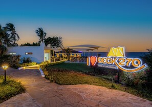A beachfront property with a sign reading 'I Love Deck 27Q Tapas Ocean Lounge.'