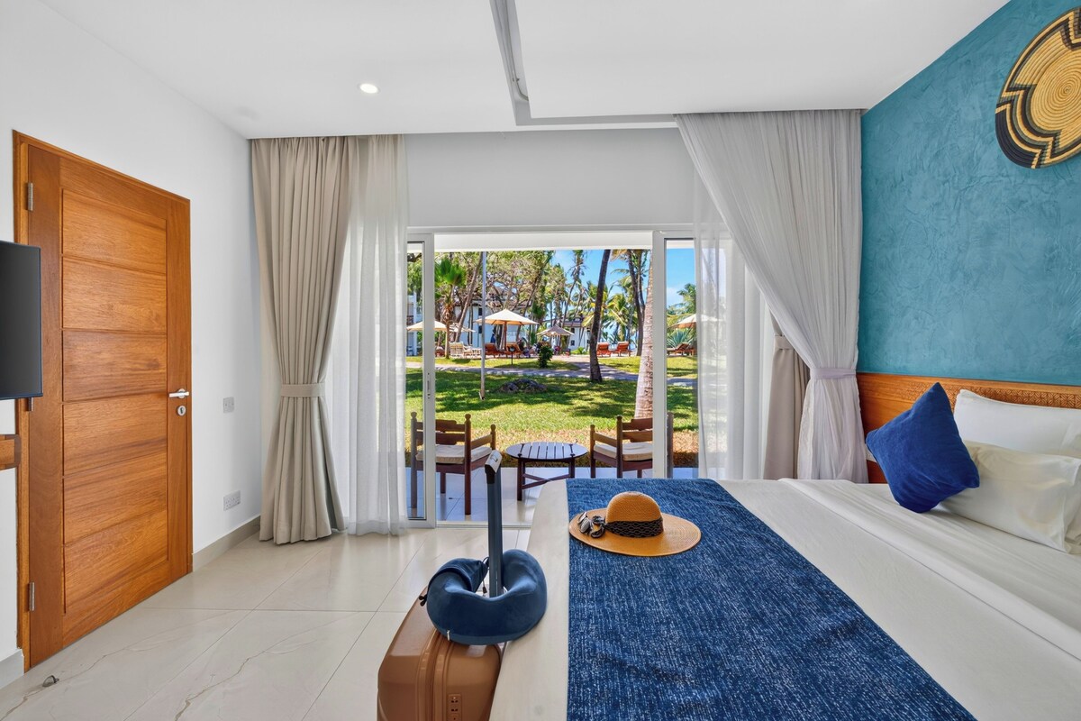 Une chambre d’hôtel avec un lit, une valise, un chapeau et une vue sur l’espace extérieur.