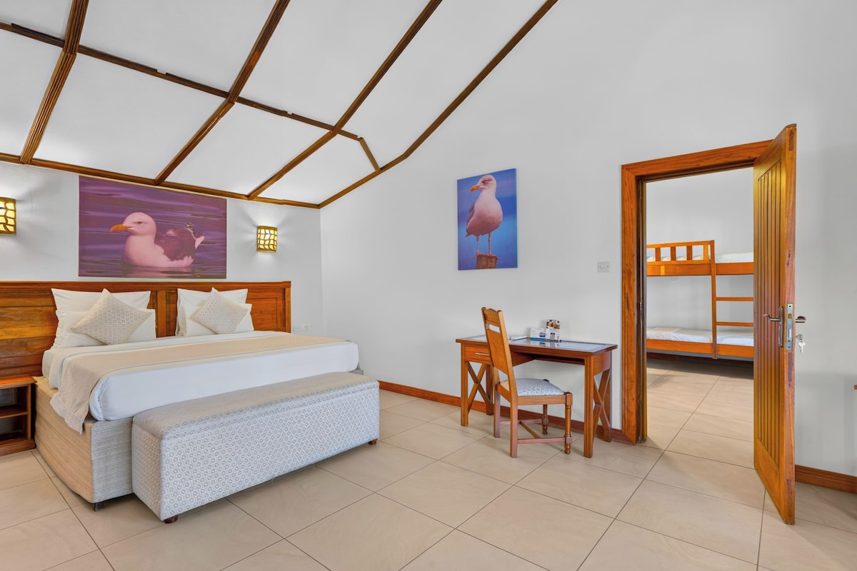 A bedroom with a bed, a desk, a chair, a bunk bed, and two wall-mounted lights.