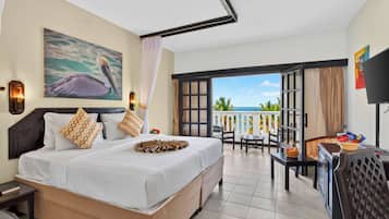 A hotel room with a bed, a painting of a pelican, a balcony with a view, and a television.