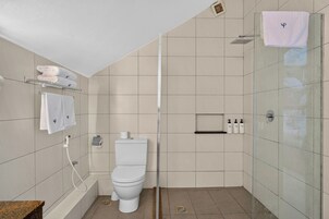 Un baño moderno con inodoro, ducha y cabina de ducha con paredes de vidrio.