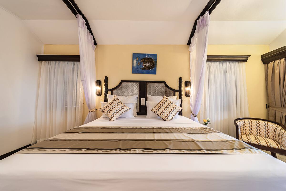 A large bed with a headboard, two side tables, and a chair.