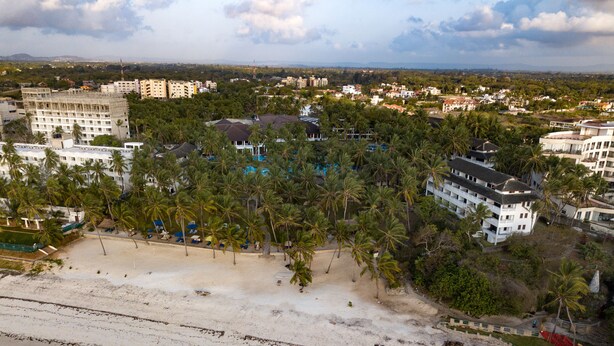 An aerial view of a coastal area with a beach, palm trees, and buildings. - PrideInn Flamingo Beach Resort & Spa Mombasa (Mombasa)