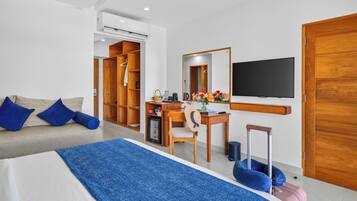 A hotel room with a bed, a desk, a chair, a TV, a wardrobe, and a small fridge.