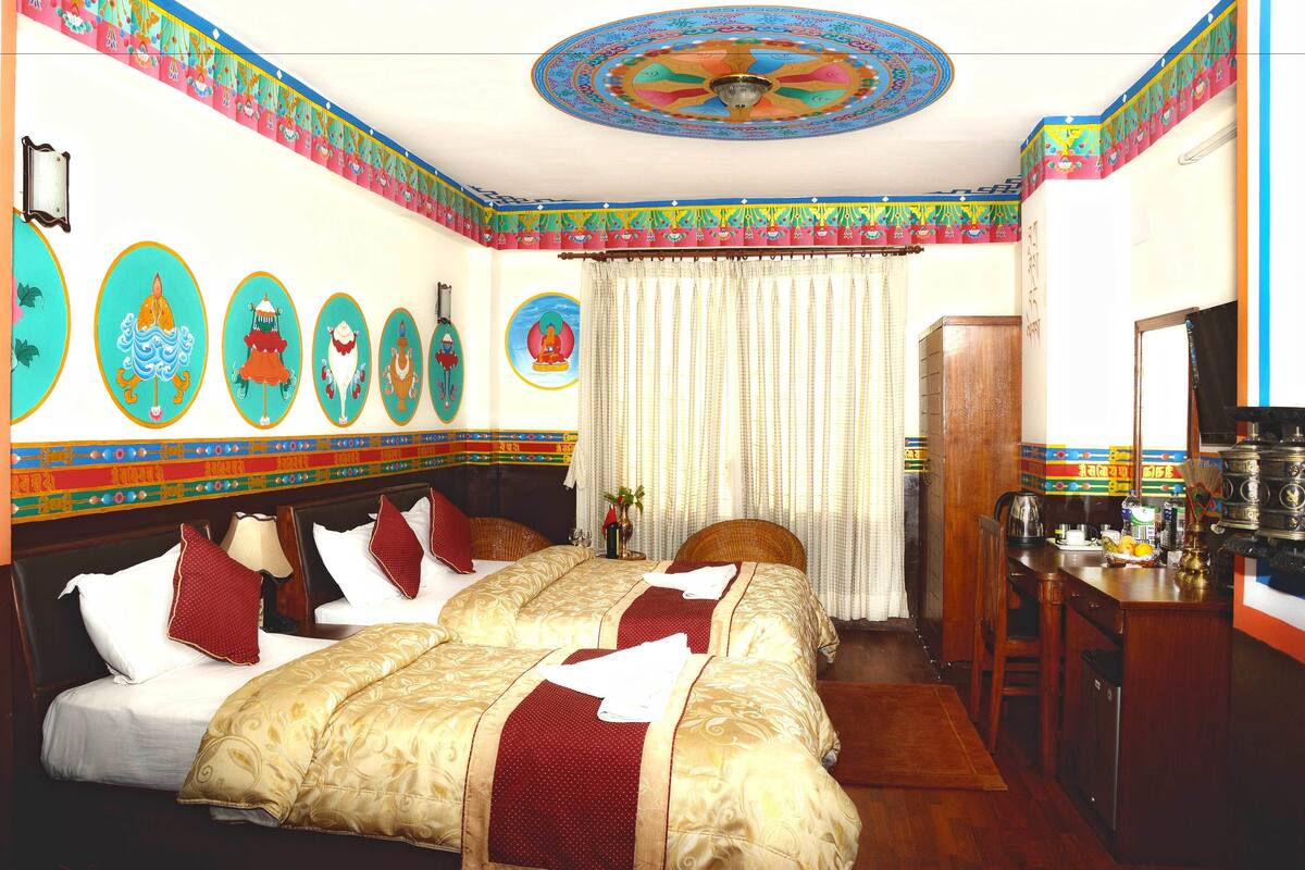 A hotel room with a large bed, a desk, and a traditional ceiling design.