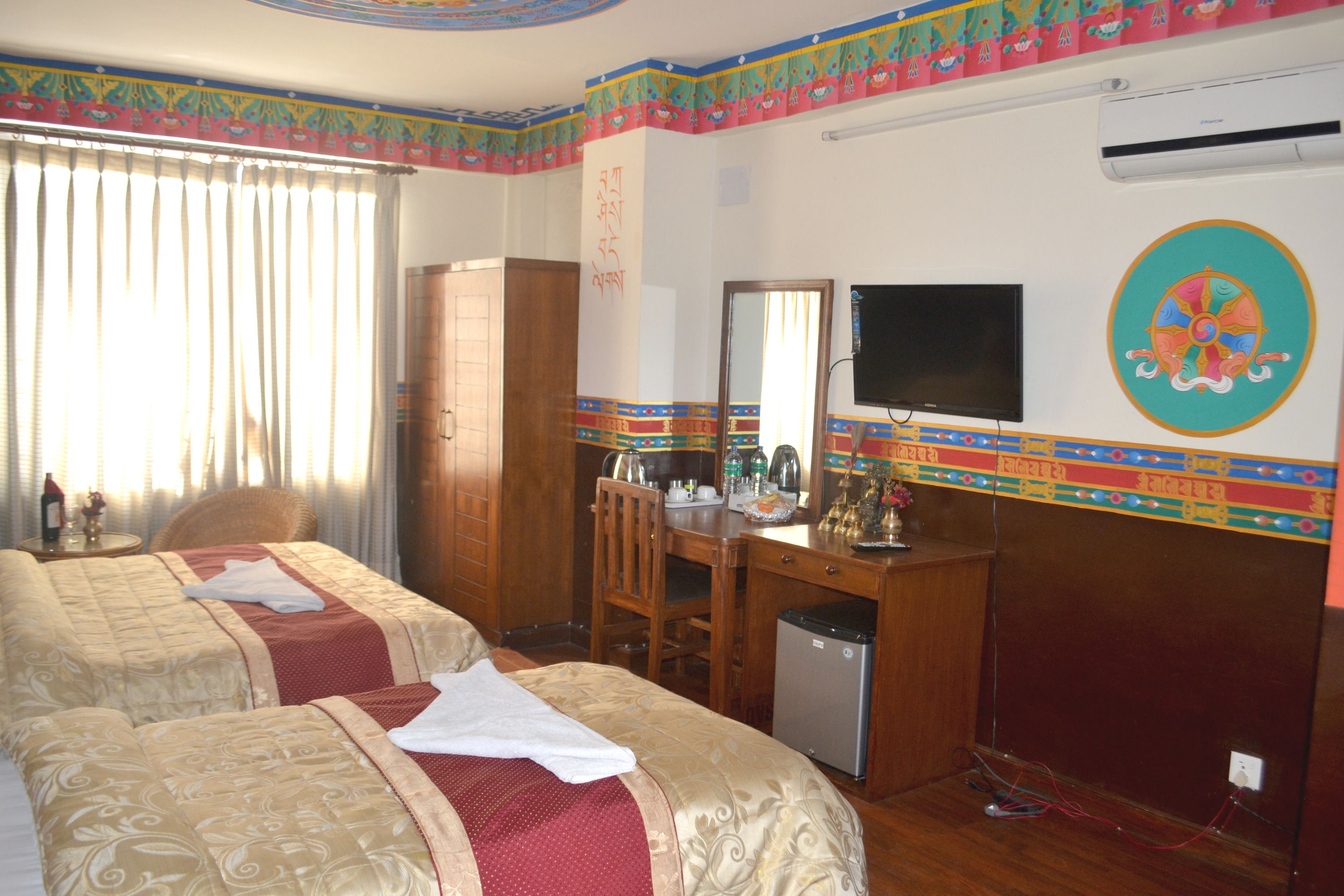 A hotel room with two beds, a desk, a chair, a television, and a wardrobe.