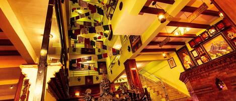 A staircase with a unique geometric pattern, a statue, and a cash register in a warmly lit interior space.
