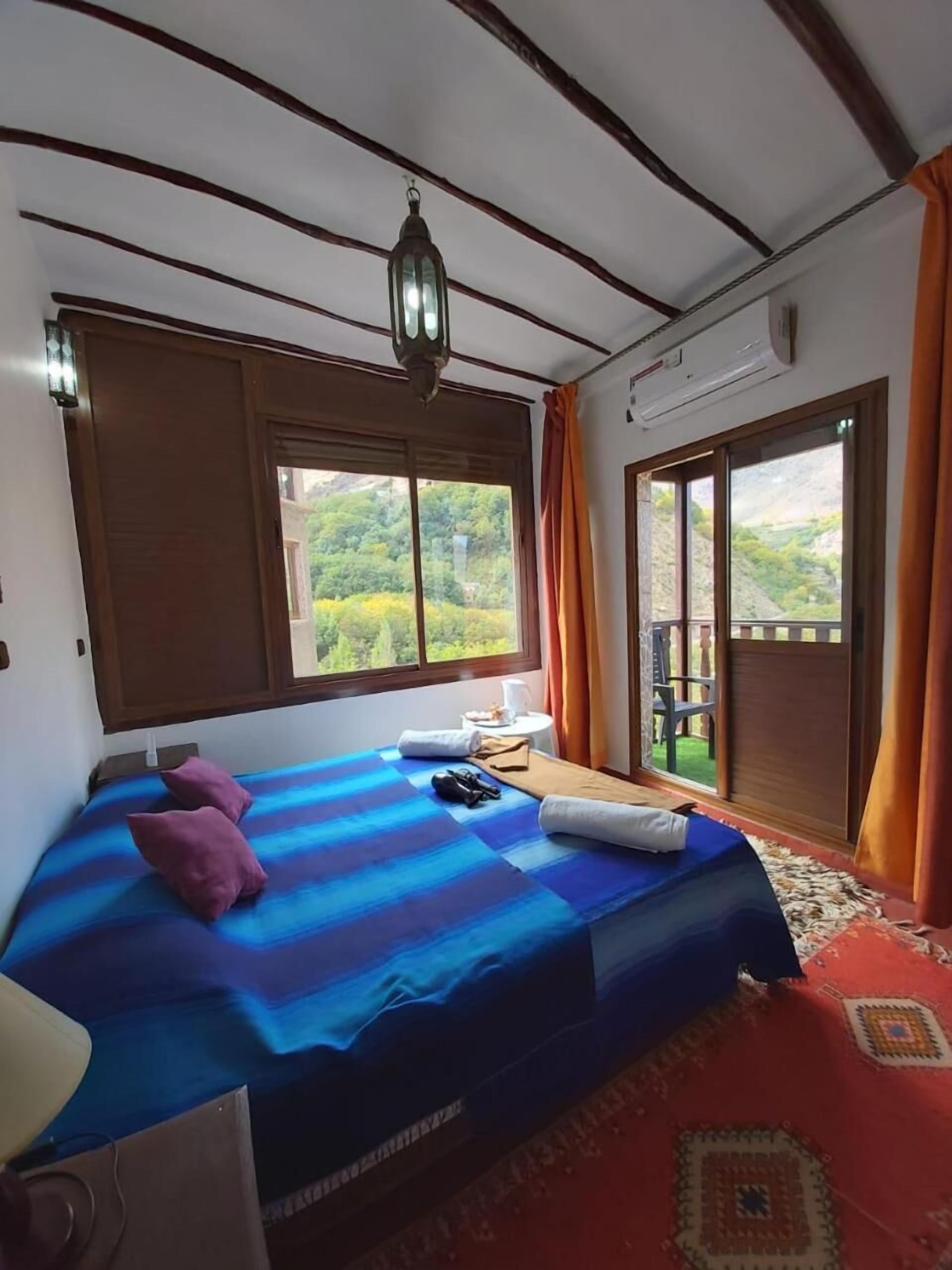 A bedroom with a bed, a window, and a view of the outdoors.